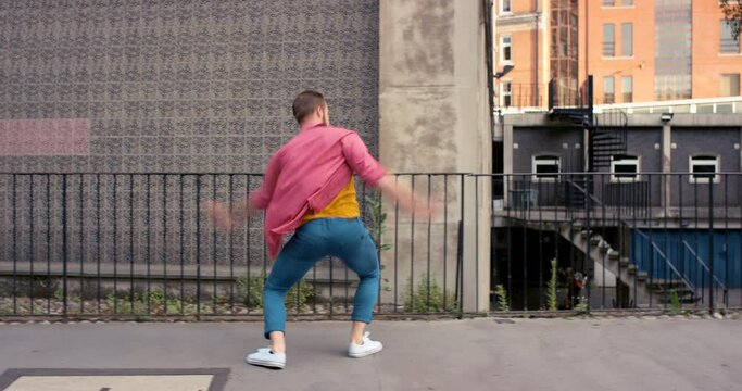 Energy, dancing and young man in city with freedom, steps and energy with music or song. Dancer, freestyle and male person moving in road for celebration of good news or achievement in urban town.