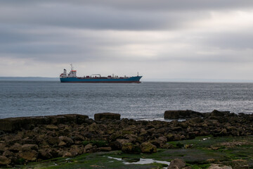 Cargo ship on the seashore in a cloudy day.