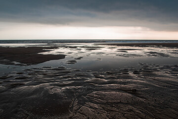 Sunset on the beach at low tide with low tide in the foreground