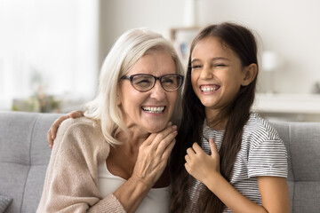 Happy granddaughter and grandmother enjoying family relation of generations, sitting on comfortable...
