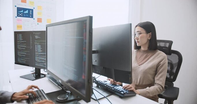 Young adult Asian male, female software developer coding program on desktop computer. Man, woman work from home, remote working, freelance programmer job, smart digital nomad lifestyle concept