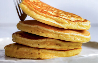 Pancakes fluffy stack on white plate, delicious food. Homemade freshly baked pancakes for American breakfast, menu, advert or package, close up.