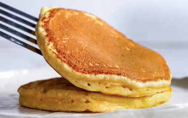 Pancakes fluffy stack on white plate, delicious food. Homemade freshly baked pancakes for American breakfast, menu, advert or package, close up.