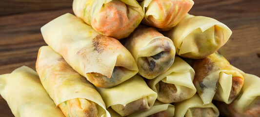 Minced beef stuffed crepes with carrot on wooden board