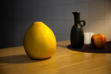 Vibrant Still Life: Red Pomelo Amidst Apples and Vase, Illuminated by Soft Mood Lighting. tiles. yellow light. blue backlight