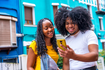 Young african friends using phone in a colorful street