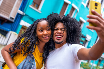 Young african couple pulling faces taking selfie int he city