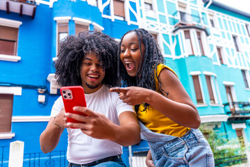 African friends pointing to a mobile with surprised expression