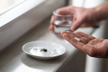 close up of male hands holding capsule pill and glass of water. Medicine pharmacy health. close up of a man taking pills