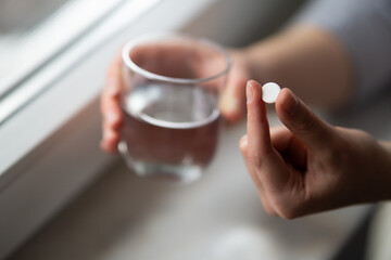 Fototapeta na wymiar woman hands holding capsule pill and glass of water close up 
