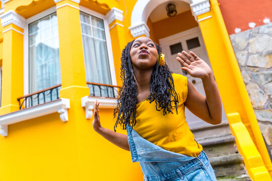 Cute african woman dancing listening to music with headphones outdoors
