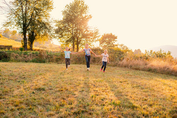 Happy family playing together outside, father and children with holding hands runing together in the summer park.