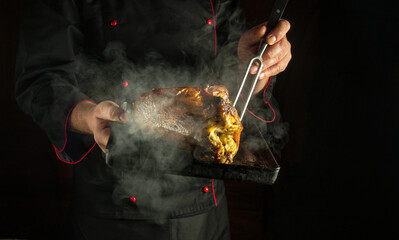 Professional chef prepares a duck. Poultry carcass with steam on a baking sheet in the cook hand....