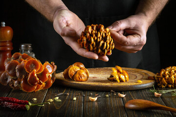 A chef sorts mushrooms with his hands in the kitchen before cooking them with spices. Mushroom diet...