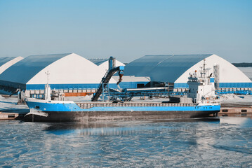 General Cargo Ship Equipped With Gantry Crane During Loading Process In The Frozen International Shipping Trade Port. Water Surface Covered With Ice. Winter Navigation in The Arctic Area Region © I am from Mykolayiv