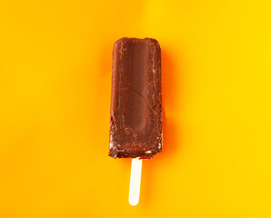 chocolate ice cream on a stick on orange background