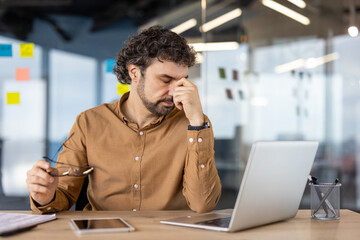 Overtired and overwhelmed businessman has dizziness and eye pain, mature experienced male worker at...