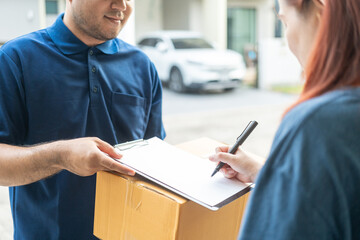 Delivery man holding a cardboard box while woman putting signature in clipboard. Hand female...