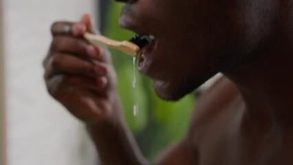 Moving shot African American male hold toothbrush with whitening toothpaste ethnic man brushing teeth cleaning gums oral care dentistry clean tooth refresh morning dental healthy hygiene in bathroom