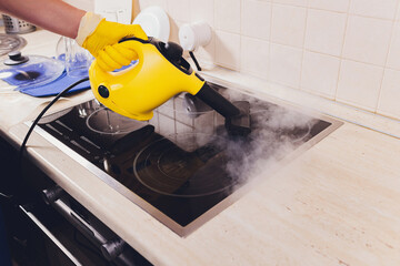 Cleaning kitchen hob with a steam cleaner.