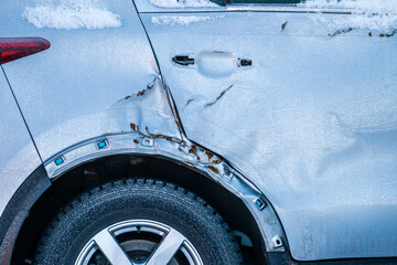 Broken rear fender and door of a grey car.