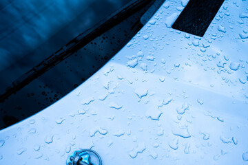 Raindrops on the hood of a grey sports car.