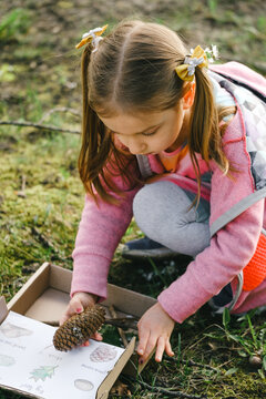 Scavenger hunt for kid in the park. Girl learning about environment. Natural education activity for World Earth day. Exploring in spring.