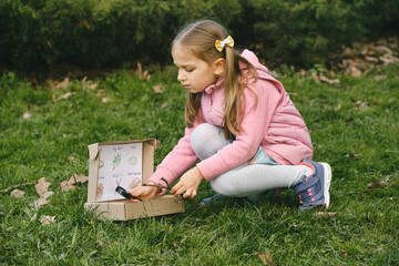 Scavenger hunt for kid in the park. Girl learning about environment. Natural education activity for...