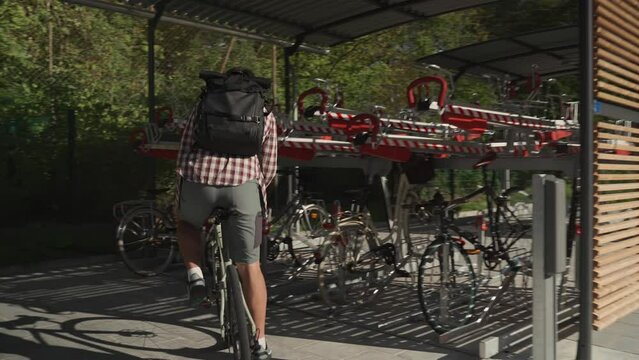 A man parks his bicycle in a modern urban multi-level bike parking lot in Munich, Germany. Cyclist uses bike urban outside parking on two floors. A male places his bicycle in a two row parking lot