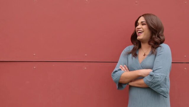 Transsexual woman on a red wall laughing and smiling. Copy space background.