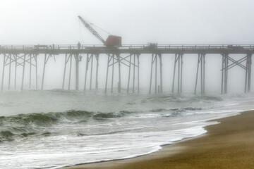 A foggy seascape of pier maintenance in progress at the pier at Kure Beach, North Carolina, in the Eastern U.S.
