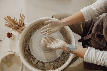 Close up of artisan's hands shaping clay bowl in pottery studio. Pottery art and creativity