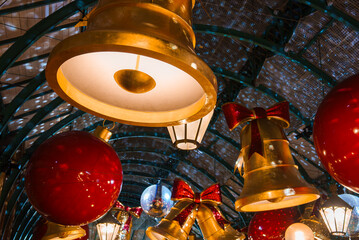 Festive Christmas decorations in London, featuring oversized red baubles and golden bells, with warm pendant lights and a vaulted ceiling in the background.
