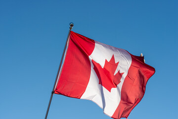 canadian flag waving against blue sky