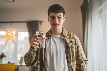 man young caucasian male teenager hold glass of water at home