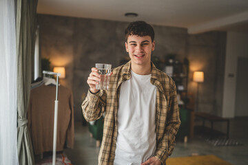 man young caucasian male teenager hold glass of water at home