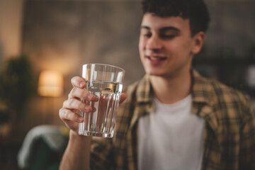 man young caucasian male teenager hold glass of water at home