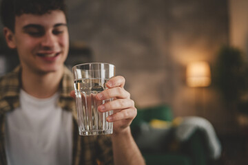 man young caucasian male teenager hold glass of water at home