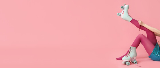 Beautiful young woman tying vintage roller skates on pink background with space for text