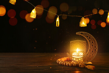 Arabic candle holder and tasbih on table against dark background