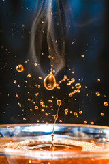 Falling drops of hot coffee on a black background, close-up
