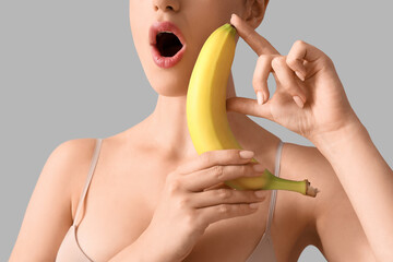 Young woman with banana on light background, closeup. Sex concept - obrazy, fototapety, plakaty