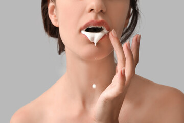Young woman with white liquid in her mouth on light background, closeup. Sex concept