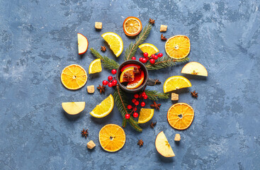 Cup of hot mulled wine with orange and apple on blue background