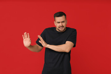 Handsome ashamed young man on red background