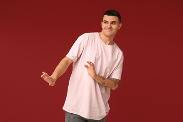 Handsome ashamed young man on red background