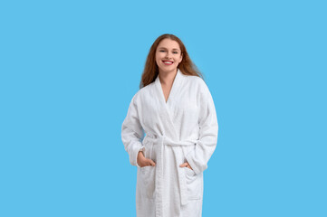 Young woman in bathrobe on blue background