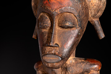 Fototapeta na wymiar Close-up of a wooden Senufo Male figure from Ivory Coast with a brown patina isolated on black. Tribal African art, showcasing masterful craftsmanship and spiritual symbolism.