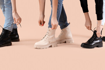 Female legs wearing different boots with laces on beige background