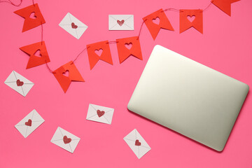 Laptop with love letters and paper garland on pink background. Concept of online dating